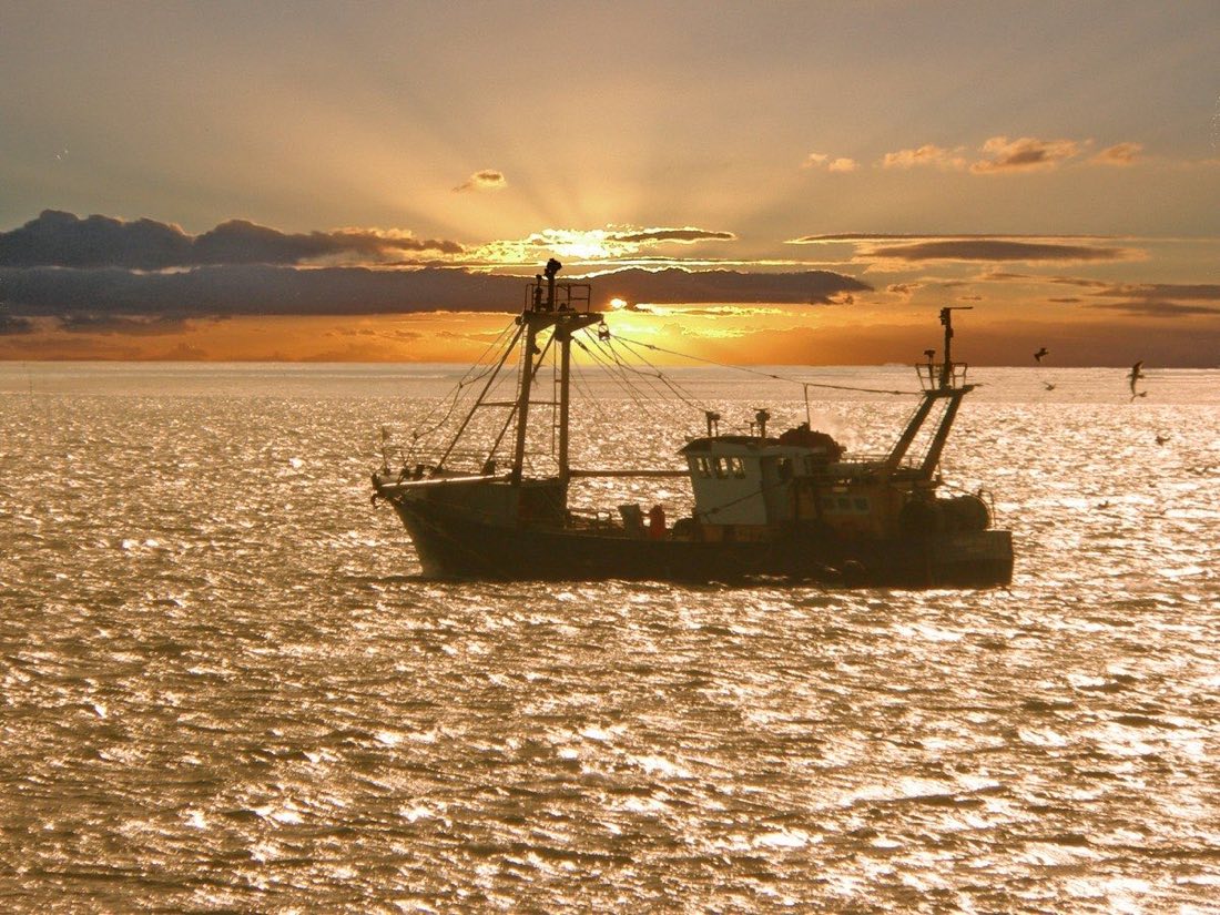 A fishing boat silhouetted against a blazing golden sunset over the sea (placeholder photo)